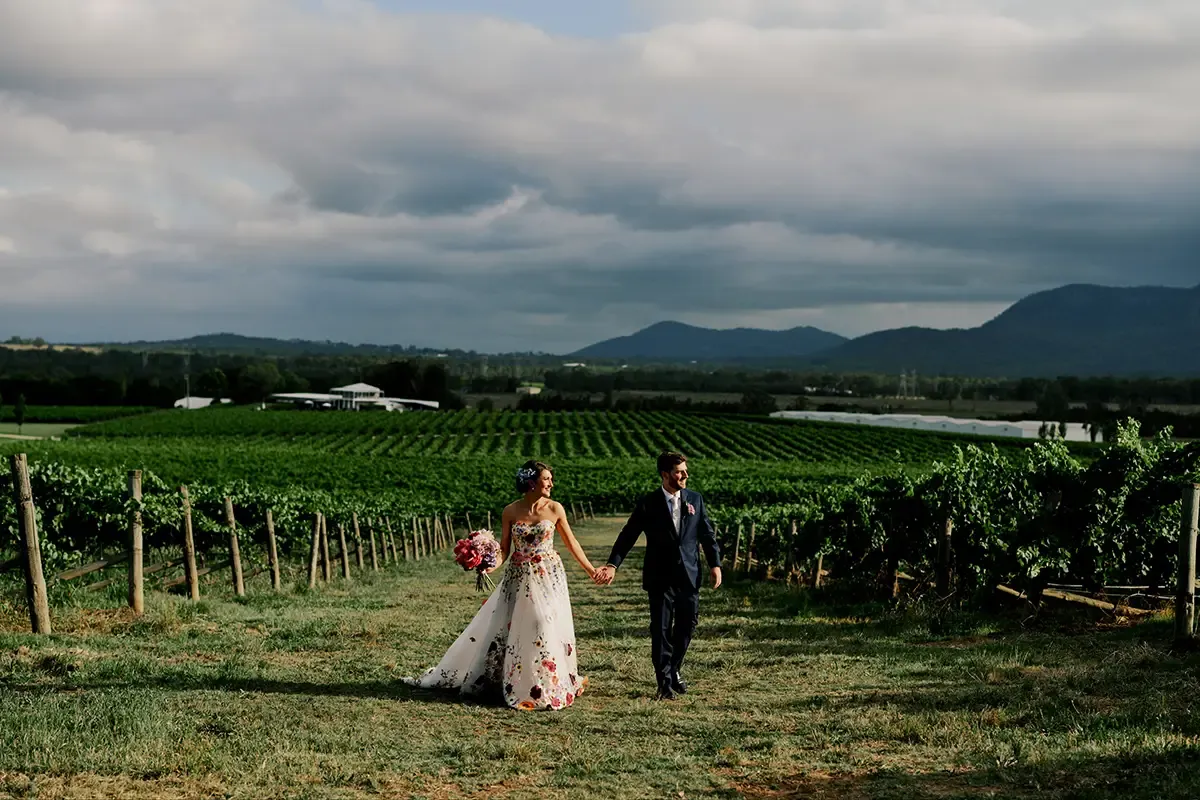 Eloping couple walking hand in hand through a Hunter Valley vineyard